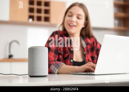 Frau spricht mit Smart Speaker. Intelligenter Assistent in einem intelligenten Heimsystem. Stockfoto