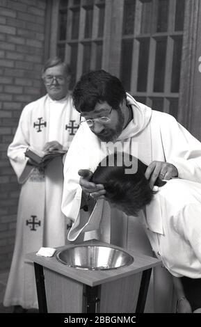 1970er Jahre, historisch, in einer Kirche, eine Frau, die sich taufen lässt, als ein bewohnter Priester ihren Kopf wetet, London, England, Großbritannien. Die Taufe ist ein christlicher Zugangsritus, ein Abendmahl, eine Verordnung Jesu Christi. Stockfoto