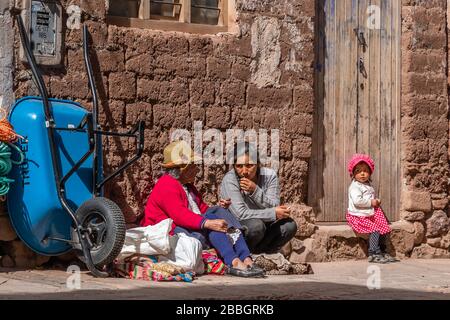 Pisac, Peru - 02.23.2020: Peruanische Frauen mit einem kleinen Mädchen, die Waren auf den Straßen von Pisac verkaufen Stockfoto