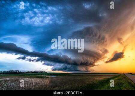 Der sich drehende Mesocyclon-Tornado warnte bei Sonnenuntergang in Saskatechewan Canada vor Sturm über die ländliche Schotterstraße und das Feld Stockfoto