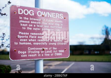 Ein Schild, das Hundebesitzer warnt, ihren Hund auf einem Gemeinschaftssportplatz an der Spitze zu halten Stockfoto