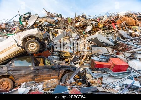 Riesiger Berg mit hauptsächlich Metallmüll, Geräten und einem Paar Autos in einem Schrottplatz. Stockfoto