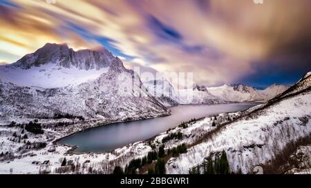 Dramatisch bewölkter Himmel über den schneebedeckten Bergen rund um den Fjord. Stockfoto