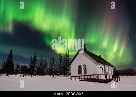 Aurora tanzt über einer alten Kirche in einer mittleren Winternacht im ländlichen Manitoba Kanada Stockfoto