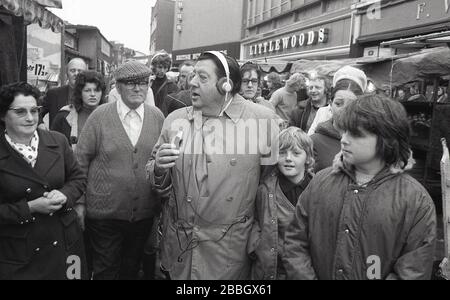 1970er Jahre, populär, Mann der Leute, Radiomoderatorin und Reporterin Monty Modlyn in einer Hochstraße in South London, als er nach jemandem sucht, der interviewt werden soll. Modlyn wurde in eine jüdische Familie aus Lambeth geboren und war für seinen Cockney-Akzent bekannt. Seine Sendung Forte interviewte normale Menschen, eine Technik, die als "Vox Pop" bekannt wurde. Als er sich mit den Worten "Ullo darlin" an die Menschen der Arbeiterklasse wendet, sah er, wie er während einer langen und hervorragenden Rundfunkkarriere sowohl im Fernsehen als auch im Radio Gespräche über alles und alles führte, sowohl für die BBC als auch für das kommerzielle Radio. Stockfoto