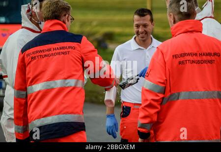 Hamburg, Deutschland. März 2020. Sanitäter der Hamburger Feuerwehr desinfizieren ihre Funkgeräte vor einem alten Volksheim, in dem mehrere Bewohner positiv auf Covid-19 getestet haben. Kredit: Axel Heimken / dpa / Alamy Live News Stockfoto