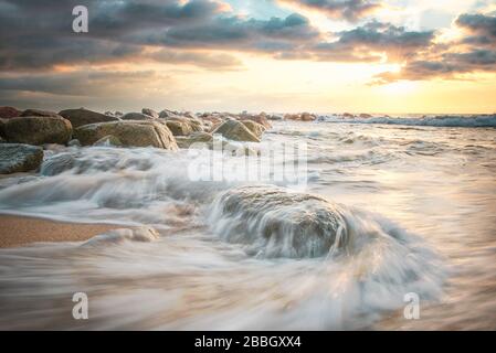 Wellen in Zeitlupe krachen bei Sonnenuntergang auf den Strand in Puerto Vallarta Mexiko Stockfoto