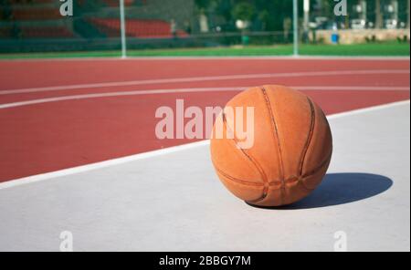 Gebrauchten Basketball im Vordergrund liegt auf einem leeren Basketballplatz mit verschwommenem Hintergrund Stockfoto