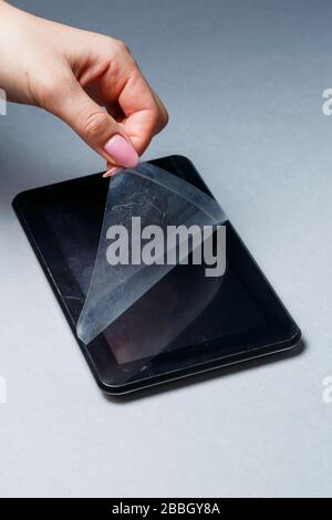 Schwarz verkratztes Tablett mit einer Schutzfolie auf grauem Hintergrund. Schützen Sie den Bildschirm Ihres Geräts Stockfoto