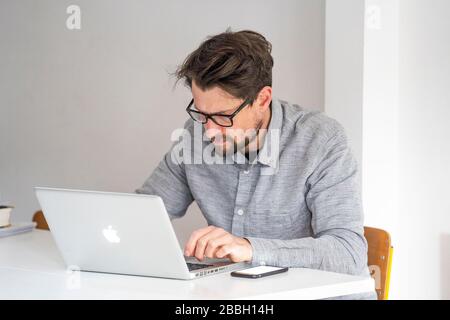 MID 40er-Mann, der von zu Hause aus mit einem Apple-Laptop arbeitet. Stockfoto