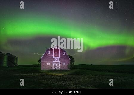 Aurora tanzt über der alten roten Scheune im ländlichen Manitoba, Kanada Stockfoto