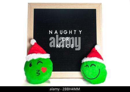 Ein Schwarz-Weiß-Schild mit einem Birch-Rahmen, das Naughty oder Nice mit einem flirren und einem fröhlichen Emoticon sagt Stockfoto