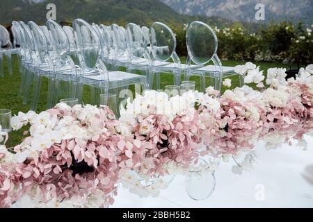 Ein wunderbarer Ort in den Dekorationen und Blumen für die Hochzeitsfeier. Mit transparenten Stühlen am Meer. Stockfoto