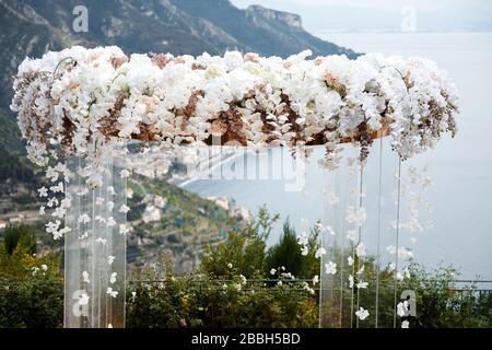 Ein wunderbarer Ort in den Dekorationen und Blumen für die Hochzeitsfeier. Mit transparenten Stühlen am Meer. Stockfoto