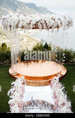 Ein wunderbarer Ort in den Dekorationen und Blumen für die Hochzeitsfeier. Mit transparenten Stühlen am Meer. Stockfoto