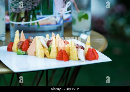 Platte mit Obst. Dekorierter Desserttisch für eine Party. Frisches, exotisches, biologisches Obst, leichte Snacks auf einem Tisch am Buffet. Stockfoto