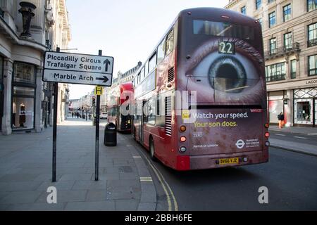 Bus mit riesigem Blick auf den Rücken eine Straßenverkehrssicherheitanzeige in der Regent Street, in Londons Haupteinkaufs- und Einzelhandelsgebiet, die normalerweise von Tausenden von Käufern und Verkehr voll ist, ist aufgrund des Coronavirus Ausbruchs am 23. März 2020 in London, England, Großbritannien praktisch verlassen. Die meisten Käufer sind nach Regierungsratschlägen zu Hause und verlassen die Straßen ruhig, leer und unheimlich. Coronavirus oder Covid-19 ist eine neue Atemwegserkrankung, die beim Menschen bisher nicht beobachtet wurde. Während ein Großteil oder Europa in den Sperrbereich versetzt wurde, hat die britische Regierung strengere Regeln als Teil angekündigt Stockfoto