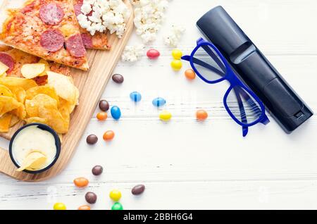 Fast Food und ungesunde Snacks, 3D-Brille und Fernbedienung auf weißem Hintergrund. Ein Stillleben-Thema, das auf der Erfahrung von 3D-Kinounterhaltung basiert Stockfoto