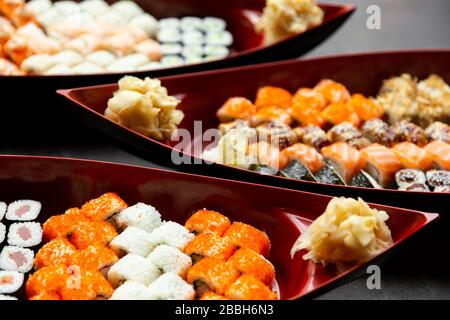 japanische Sushi-Küche. Verschiedene Sushi-Arten werden auf einem Boot aus nächster Nähe serviert. Großer Satz Brötchen auf einem Teller in einem Restaurant. Stockfoto