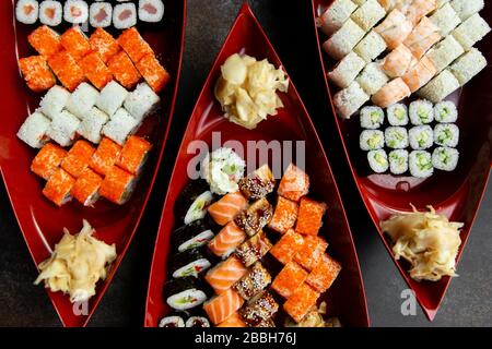 japanische Sushi-Küche. Verschiedene Sushi-Arten werden auf einem Boot aus nächster Nähe serviert. Großer Satz Brötchen auf einem Teller in einem Restaurant. Stockfoto