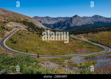 Hohe Winkellandschaft der Straßenkurve in einem grünen Tal mit Bergspitzen oben auf dem Cottonwood Pass in Colorado Stockfoto