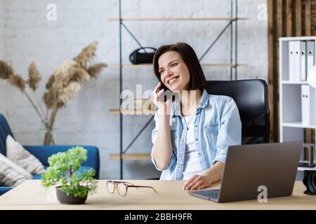 Online von home.Communication mit Kollegen und Freiberuflern arbeiten.Porträt junger Freiberufler im Gespräch mit Smartphone und Lächeln. Konzept Stockfoto