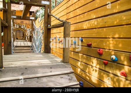 Bunte Haken für Kletterer an der Holzwand auf dem Spielplatz im Freien. Stockfoto