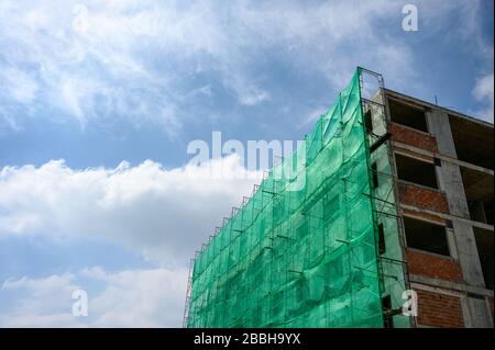 Baukörper mit Netzschatten und Gerüst bedeckt und blauer Himmel Stockfoto