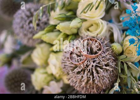 Nahaufnahme der Hochzeitsringe auf rustikalem Blumenstrauß Stockfoto