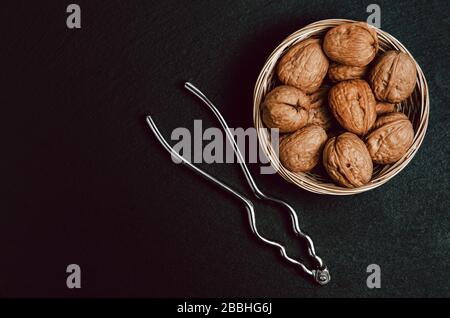 Walnüsse mit Nussknacker auf schwarzem Hintergrund, Ansicht von oben. Stockfoto