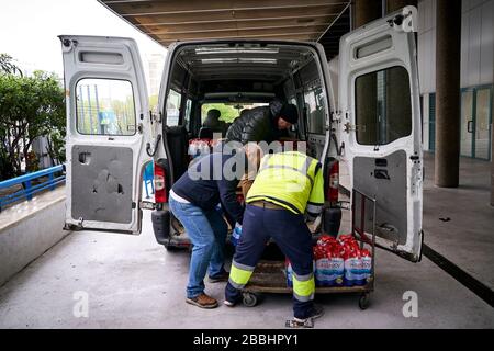 Auslieferungsleute laden das gespendete Wasser ab. 'Federacion de Penas' von Mostoles spendet 4000 l Mineralwasser an das Universitätskrankenhaus von Mostoles, um bei der Bekämpfung der Corona-Virus-Pandemie zu helfen. Stockfoto