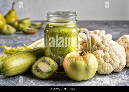 Grüner gesunder Smoothie aus grünem Gemüse und Obst auf grauem Betongrund. Gesundes Lebensmittel- und Diätkonzept. Stockfoto