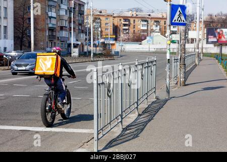 Ein Mann bewegt sich auf einem elektrischen Fahrrad entlang der Fahrbahn auf dem Bürgersteig einer Stadtstraße - ein modernes Konzept der Bewegungsfreiheit. Stockfoto