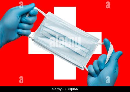 Medic hält Atemmaske in den Händen in blauen Handschuhen auf der Hintergrundfahne der Schweiz. Konzept Coronavirus Quarantäne, Grippe, Pandemie-Grippe Stockfoto