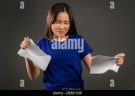 Wütende wütende asiatische Frau, die zerknittertes Papier wirft, nervösen Zusammenbruch bei der Arbeit hatte, Stressmanagement. Ernsthafte Studenten zerreißen Papiere. Stockfoto
