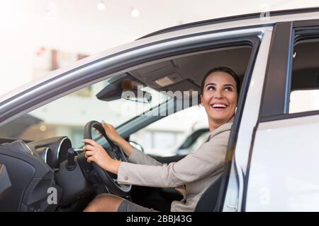 Junge Frau im Autoshowroom Stockfoto
