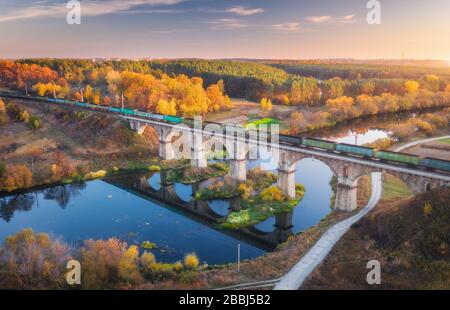 Luftbild des Güterzugs auf Eisenbahnbrücke und Fluss Stockfoto