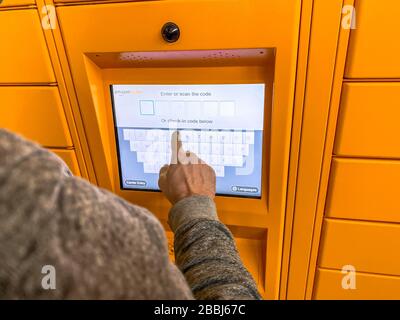 Mann, der Amazon locker im Einkaufszentrum verwendet, orangefarbene Abholstelle für Versandartikel mit dem Logo der Marke Amazon. Mobile Fotografie. Lyon, Frankreich - F. Stockfoto