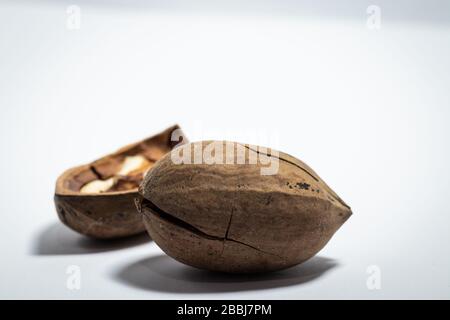 Nahaufnahme von Pekannüssen, eines gebrochen, auf weißem Hintergrund Stockfoto