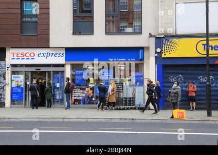 Soziale Isolierung von Warteschlangen außerhalb von Supermärkten in der Coronavirus Pandemie an der Camden High Street in London, Großbritannien Stockfoto