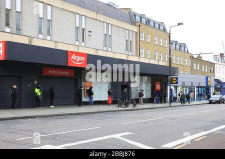 Soziale Isolierung von Warteschlangen außerhalb von Supermärkten in der Coronavirus Pandemie an der Camden High Street in London, Großbritannien Stockfoto