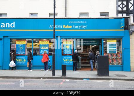 Soziale Isolierung von Warteschlangen außerhalb von Supermärkten in der Coronavirus Pandemie an der Camden High Street in London, Großbritannien Stockfoto