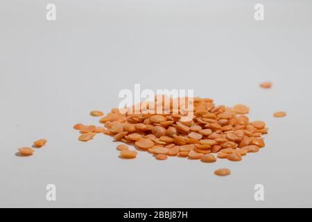 Nahaufnahme einer Gruppe zerbrochener roter Linsensamen, weißer Hintergrund Stockfoto