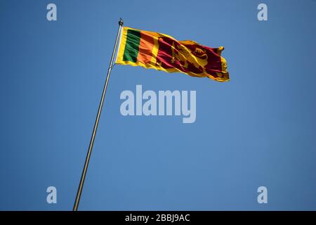 Flagge Sri Lankas schwenkt auf einen Pfosten gegen den klaren blauen Himmel Stockfoto