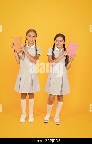 Alphabetisierung Club. Süße Kinder holding Bücher auf gelben Hintergrund. Kleine Mädchen mit Lexikon oder Bücher der Kinder. Pädagogische Bücher für Schulen. Bücher zu lesen. Schule Bibliothek. Homeschooling Konzept. Stockfoto