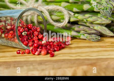 Rote Pfeffererbsen mit Spargel auf Holzbrett. Erbsenpfeffer. Rote Paprika Nahaufnahme - Hintergrund Stockfoto