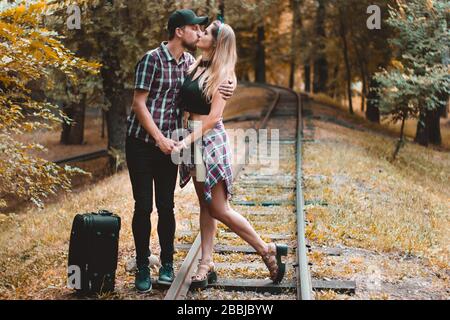 Ein junges Liebespaar verpasste den Zug. Ein Kuss auf den Schienen im Herbstwald wartet auf den nächsten Zug. Stockfoto