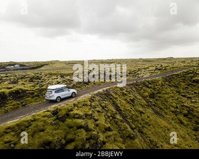 Luftaufnahme des Autos, das durch moosbedeckte Lavagesteine in IC fährt Stockfoto