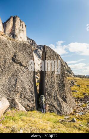 Backpacker quetscht durch Spalt in rissig unregelmäßigen Boulder Stockfoto