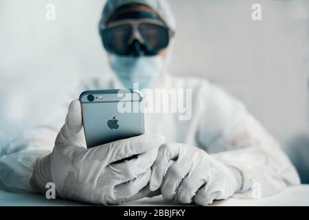 Bishkek, Kirgisistan - 14. März 2020: Bio hazrd man with iphone. Mann sucht Situation in der Welt, im Schutzanzug. Stockfoto